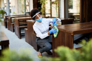 Cafe owner cleaning tables with disinfectant while reopening dur