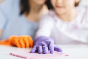 little-girl-and-her-mom-cleaning-table-surface-from-dust